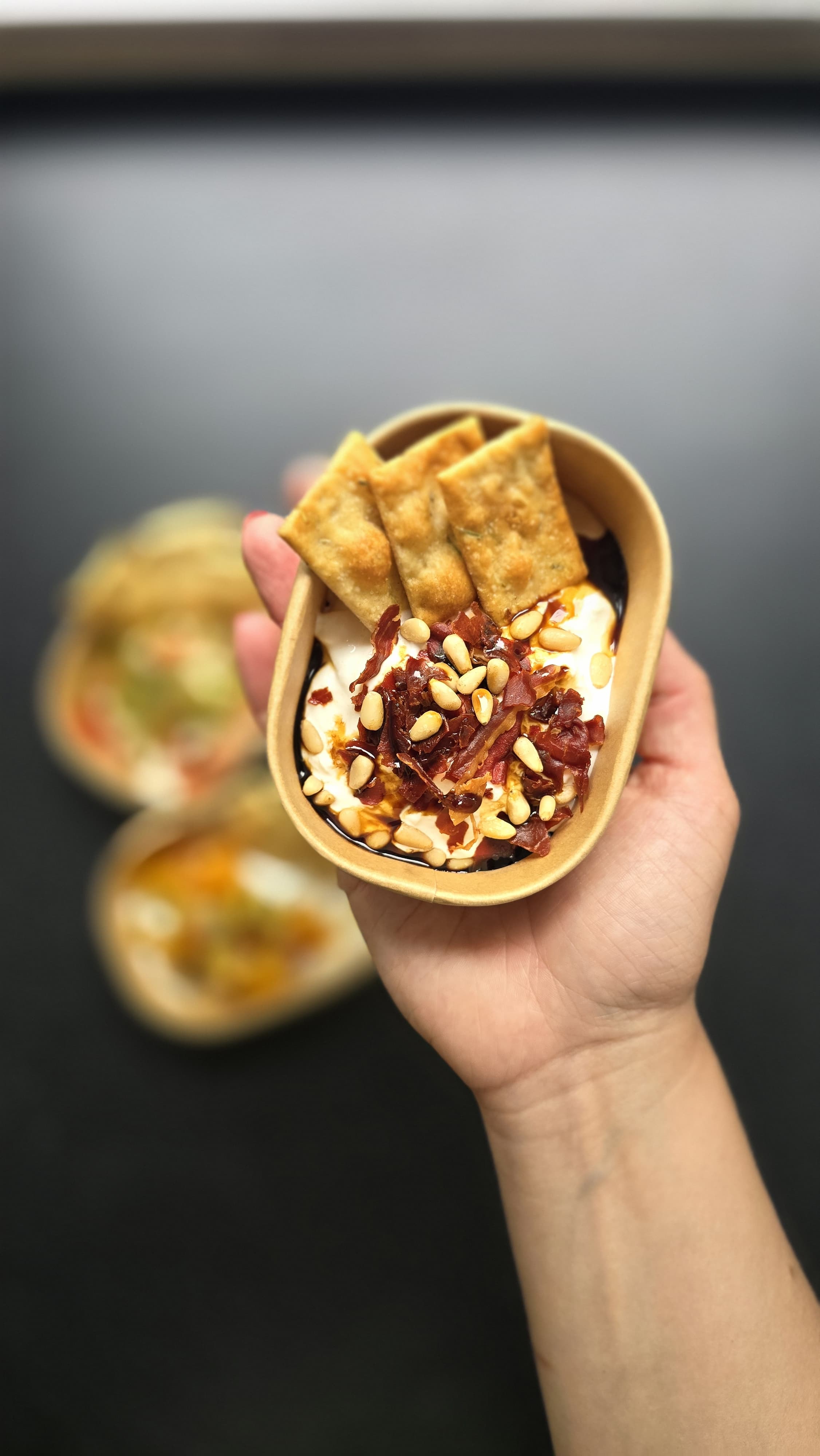 Burrata-bowl met crispy prosciutto, pijnboompitten en balsamico, vastgehouden tijdens een live burrata bar