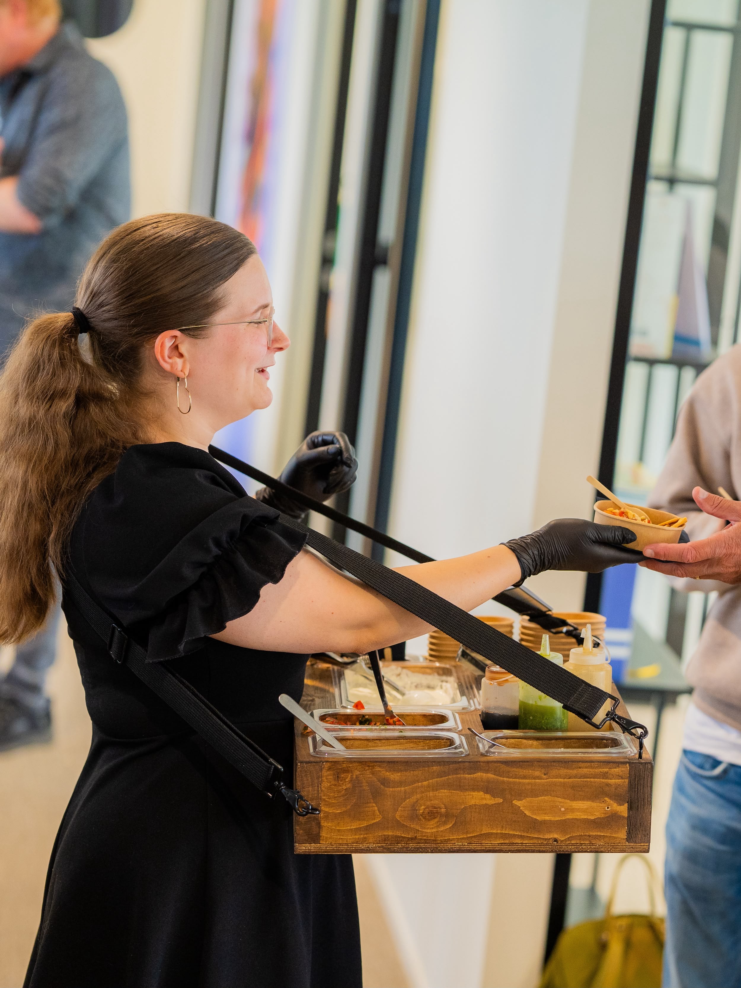 Charlotte geeft een gast een vers opgemaakte portie vanaf het hangende dienblad