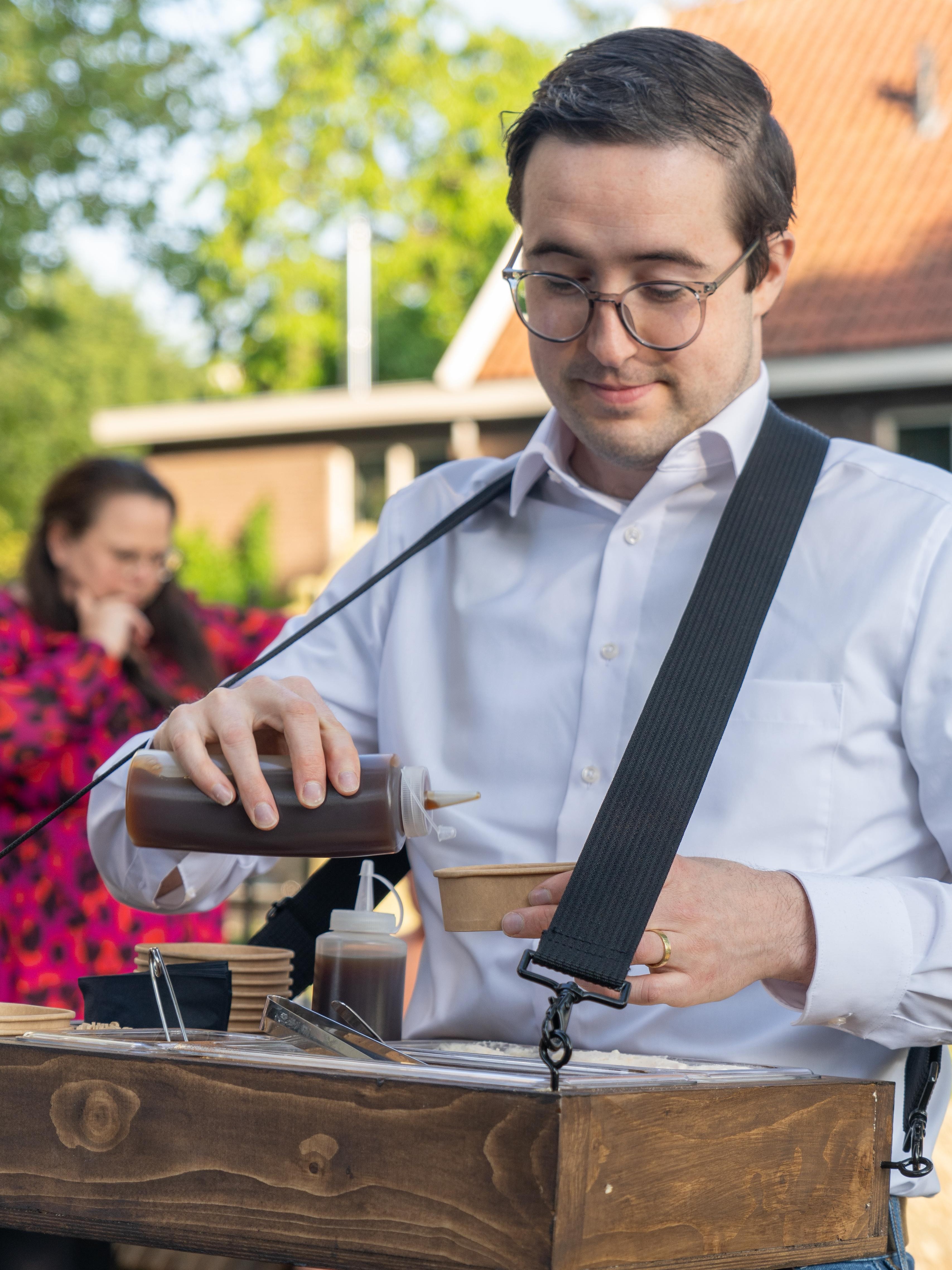 Gijs maakt een burrata-bowl af met saus, tussen de gasten van een evenement