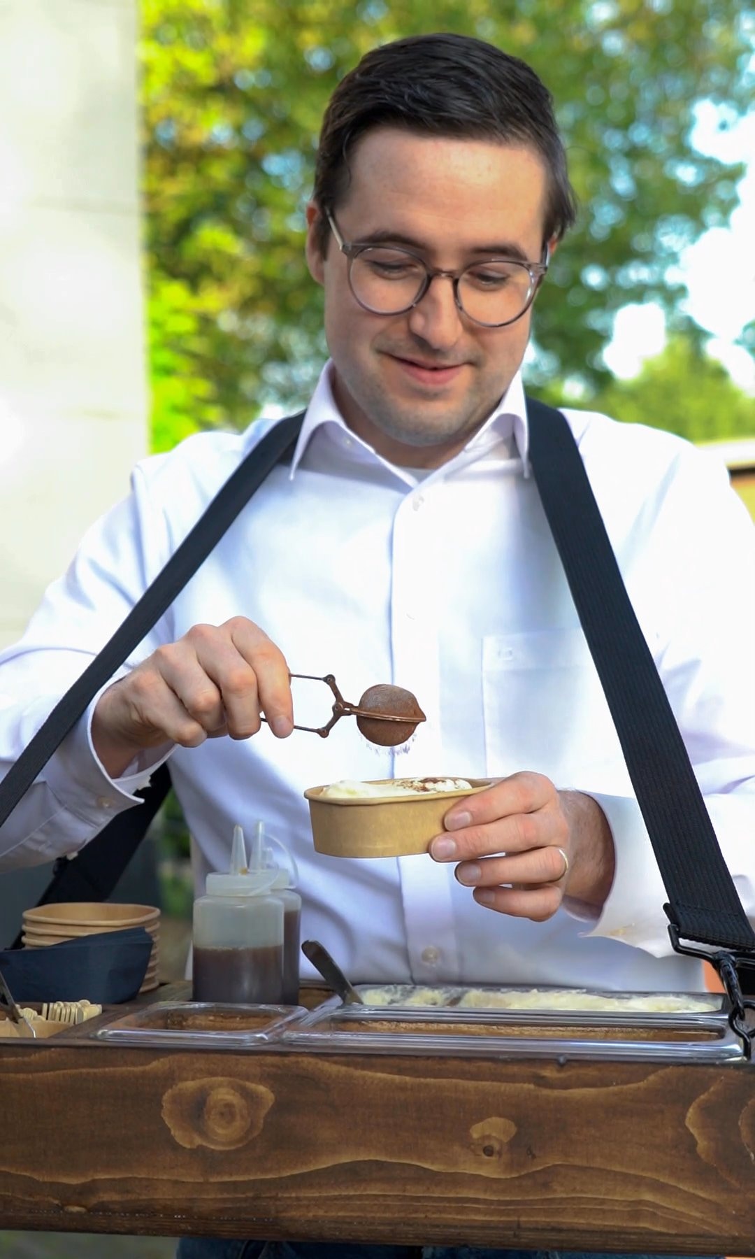 Gijs strooit cacao over een verse portie tiramisu boven het dienblad